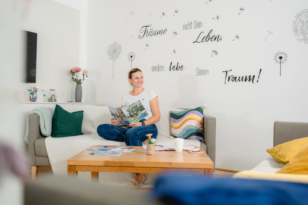 Frau sitzt in Wohnumgebung auf dem Sofa